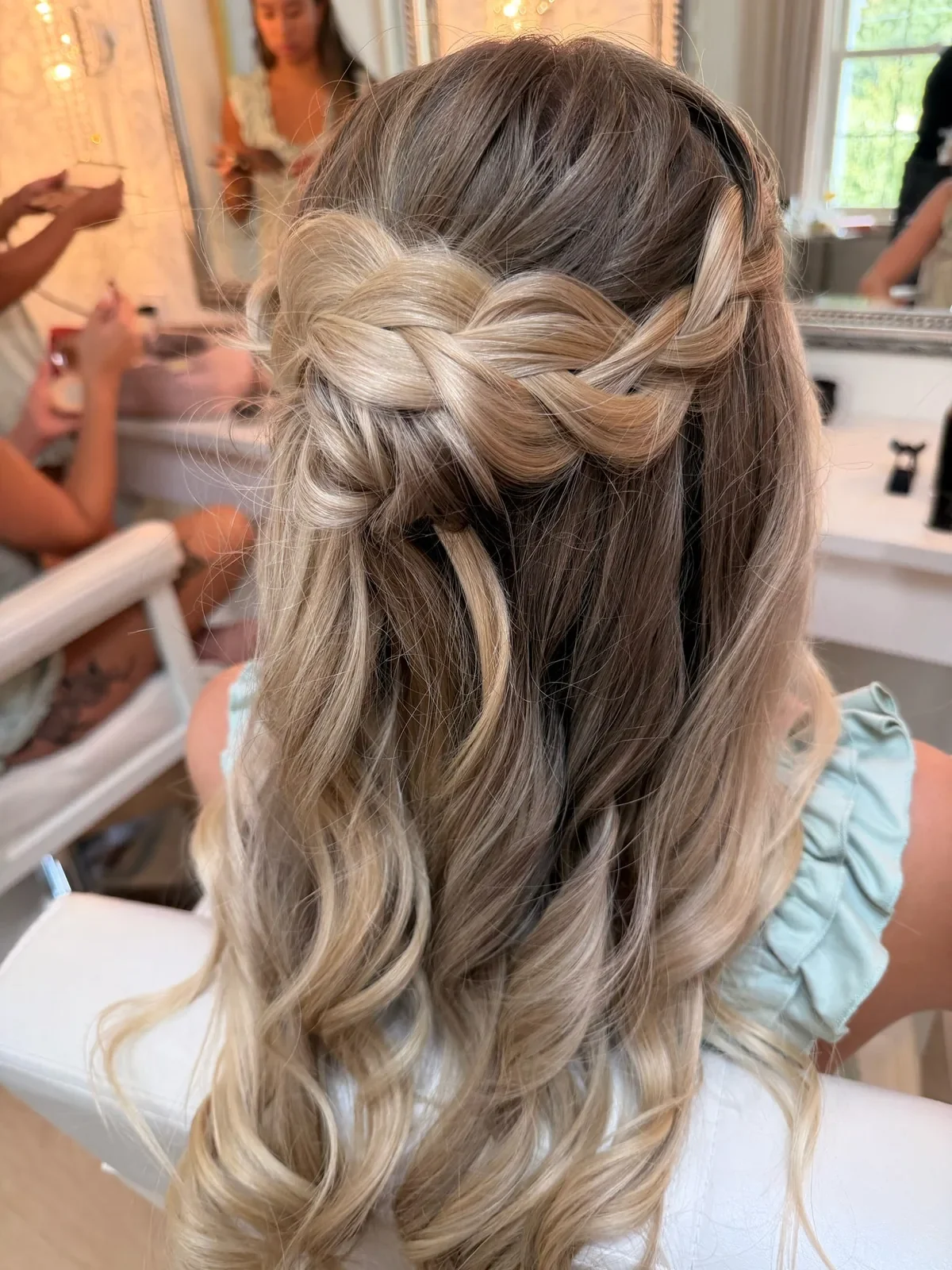 Blonde bridesmaid with braided half-up hair and long waves