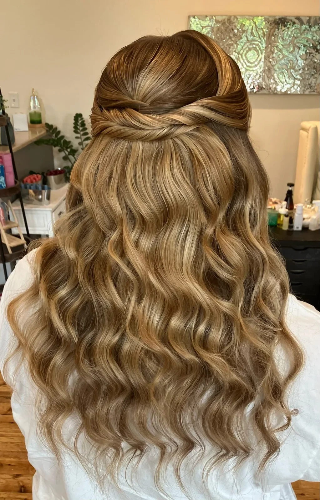 Back view of blonde bridal hair with a twisted half-up style and soft waves