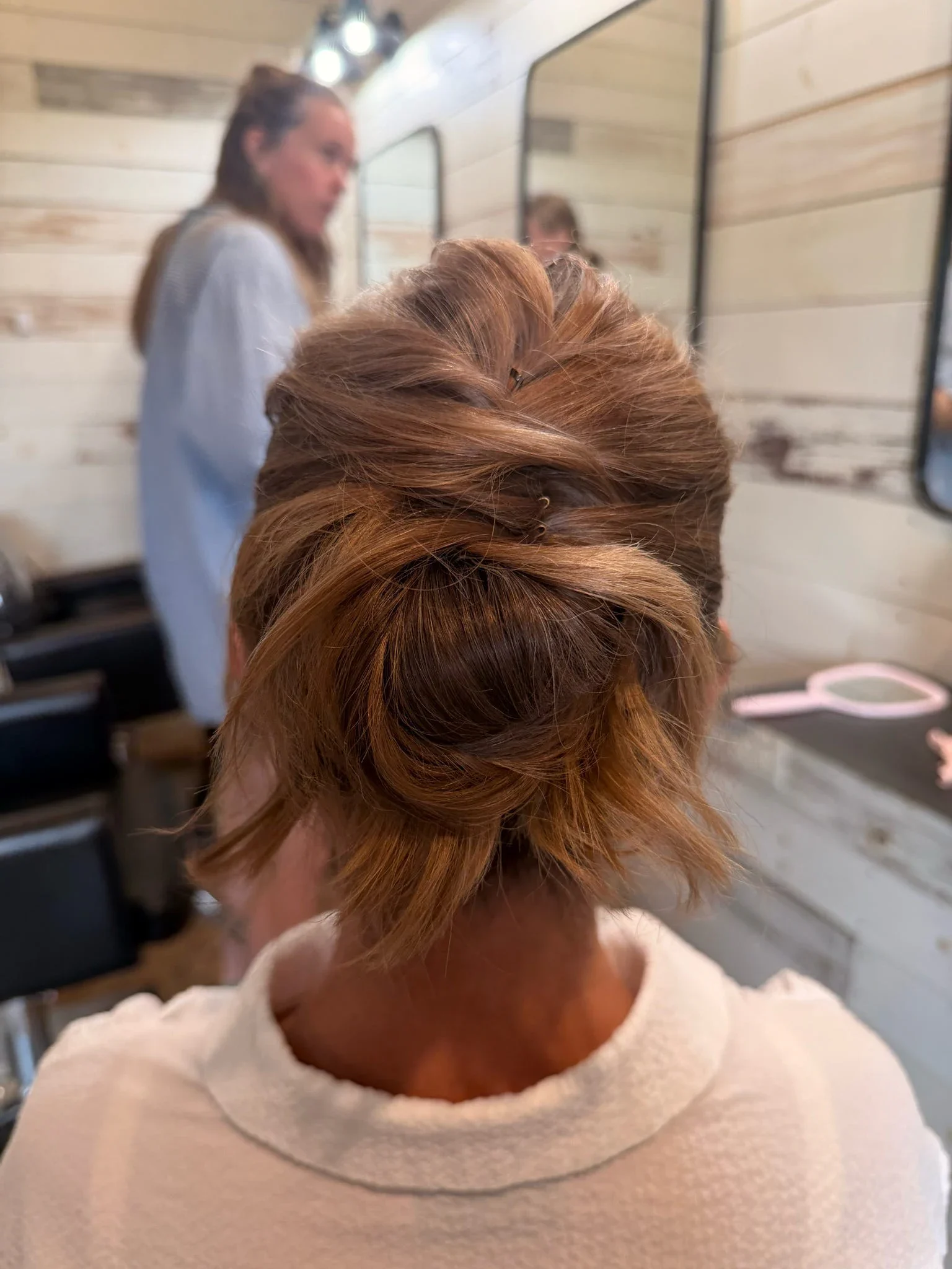 Back view of an auburn twisted low updo with a polished finish