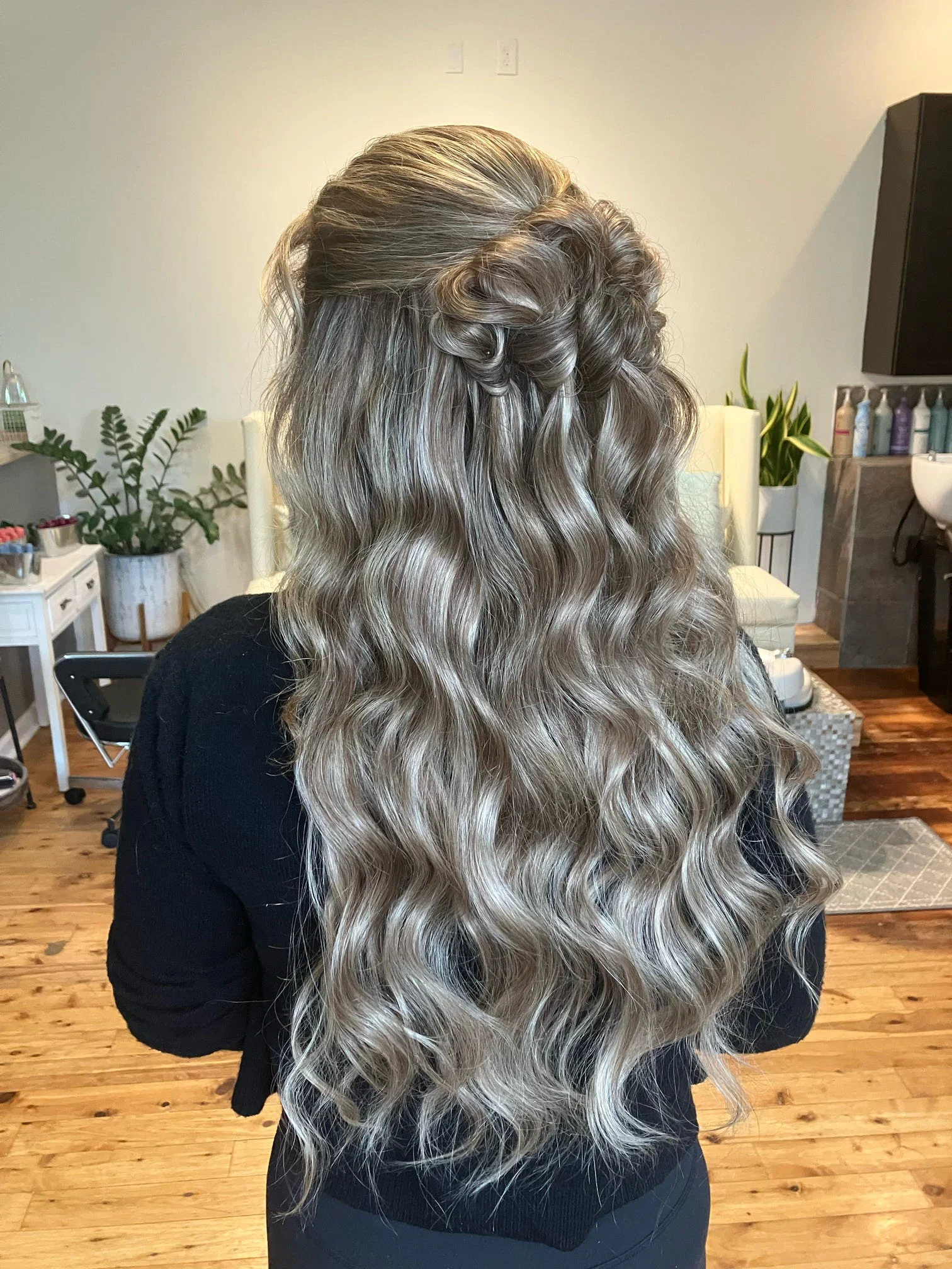 Back view of long blonde half-up waves with a sculpted rosette detail