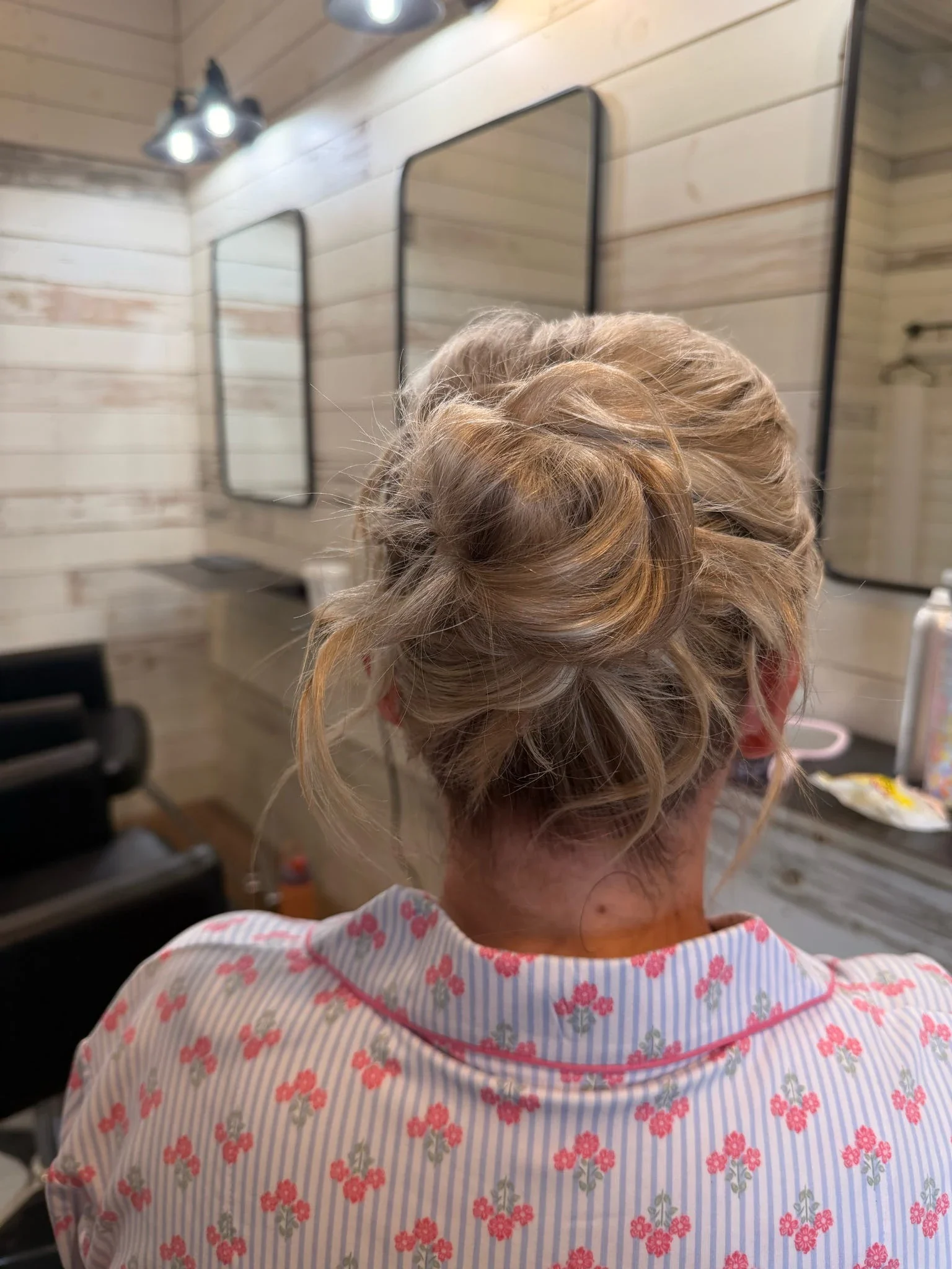 Back view of a softly textured blonde updo with loose face-framing pieces