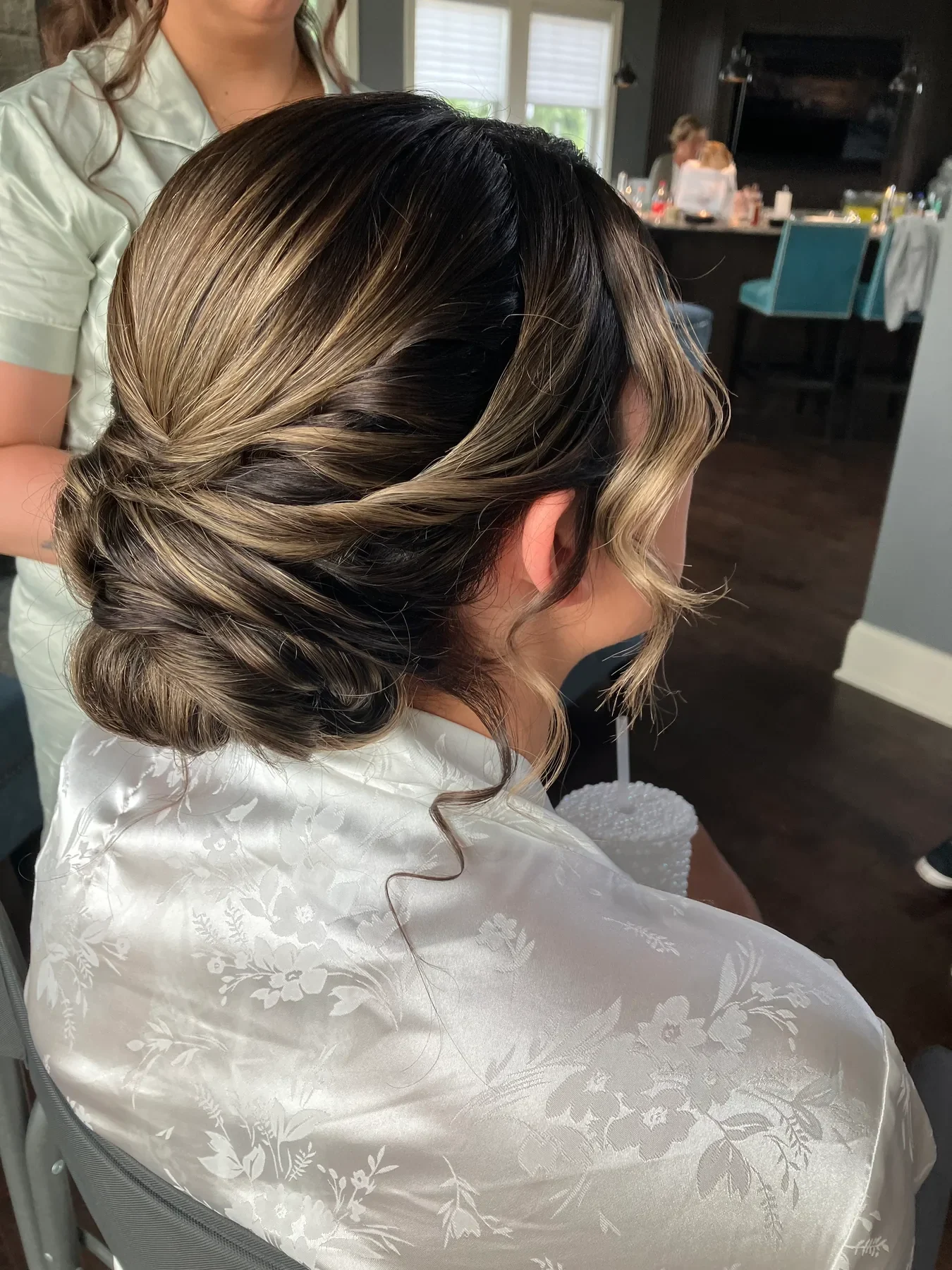 Polished bridesmaid low updo with dimensional highlights and face-framing curls