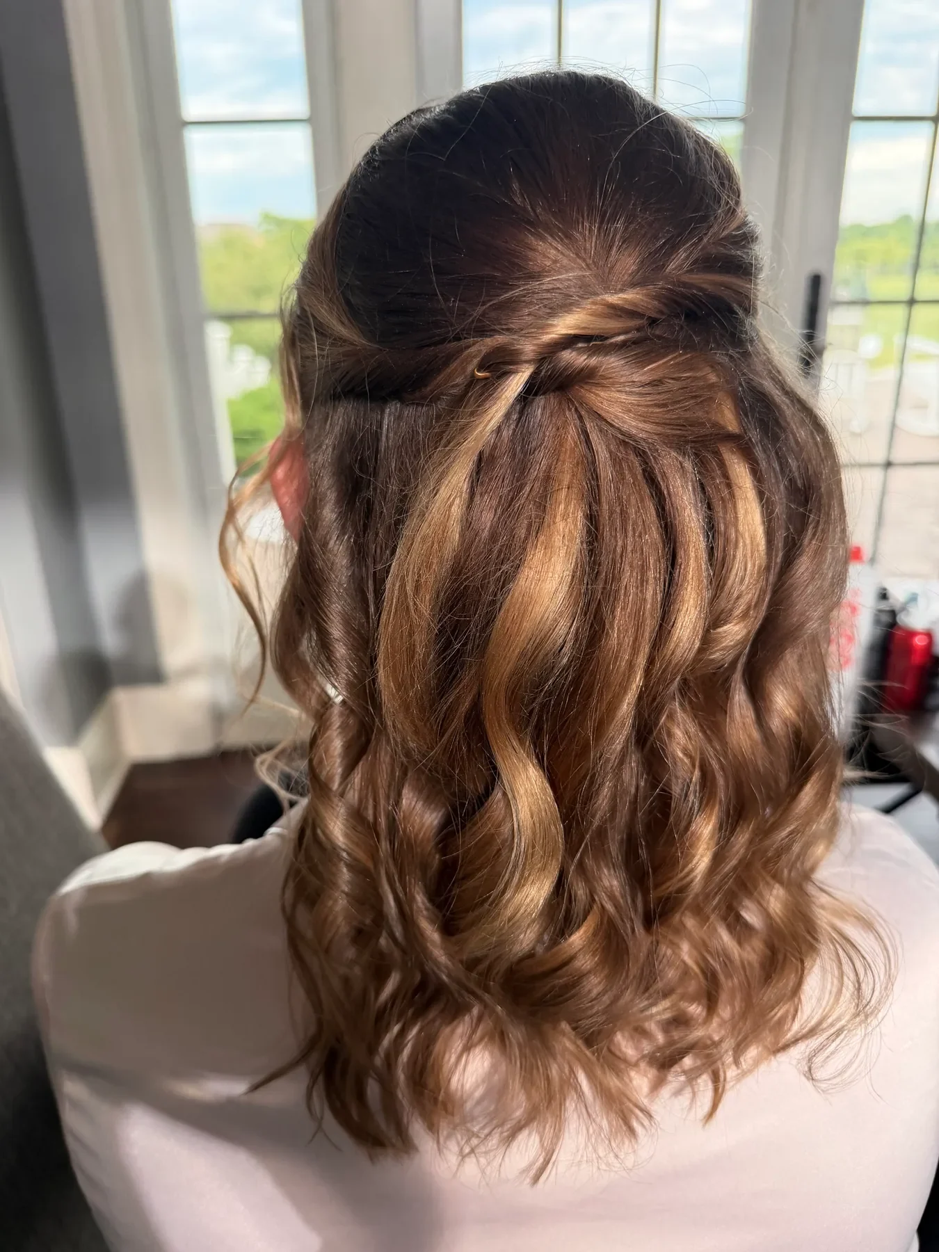 Brunette half-up wedding hairstyle with twisted detail and soft curls